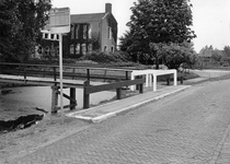 847406 Gezicht op een houten voetgangersbrugje over het water bij het gemeentehuis van Lopik (links, Raadhuisplein 1), ...